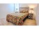 Bright bedroom featuring a queen bed with paisley bedding, shuttered windows and unique end tables at 7765 Sw 86Th Loop, Ocala, FL 34476