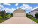 View of a two car garage with an extra long driveway and a well-manicured lawn at 7765 Sw 86Th Loop, Ocala, FL 34476