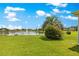 Backyard with lush lawn meets the lake, creating a peaceful scene under a blue sky at 9415 Se 125Th St, Summerfield, FL 34491