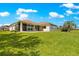 Rear exterior view of home featuring a covered patio and a well-manicured lawn at 9415 Se 125Th St, Summerfield, FL 34491
