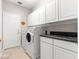 Functional laundry room with front load washer and dryer, white cabinetry, and granite countertops at 9415 Se 125Th St, Summerfield, FL 34491