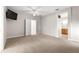 Carpeted primary bedroom with a ceiling fan, mounted TV, and an en-suite bathroom at 9415 Se 125Th St, Summerfield, FL 34491