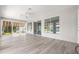Bright sunroom with wood-look floors, ceiling fan, and large windows overlooking the lush backyard at 9415 Se 125Th St, Summerfield, FL 34491