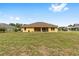 The yellow back exterior overlooks a large grassy backyard with mature trees at 9562 Sw 45Th Ave, Ocala, FL 34476