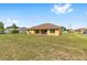 View of the house's yellow back exterior and covered patio, surrounded by a large grassy backyard at 9562 Sw 45Th Ave, Ocala, FL 34476