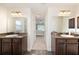 Bright bathroom featuring dual vanities with dark wood cabinets, granite countertops, and a view into the bedroom at 9562 Sw 45Th Ave, Ocala, FL 34476