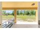 Covered patio with a chair, overlooking a spacious, grassy backyard and a red barn-like structure at 9562 Sw 45Th Ave, Ocala, FL 34476