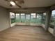 Bright sunroom featuring wood-look flooring and large windows offering outdoor views, with a ceiling fan for added comfort at 9706 Sw 92Nd Place Rd, Ocala, FL 34481