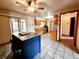 Bright kitchen features a center island, tiled floors, wooden cabinetry, and a ceiling fan at 16905 Sw 30Th Avenue Rd, Ocala, FL 34473