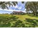 View of the back of the home showing a lush lawn with large mature trees and a cozy outdoor seating area at 10600 Se 32Nd Ave, Ocala, FL 34480
