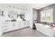 Bright bathroom featuring a freestanding tub, dual sinks, and gray tile flooring at 10600 Se 32Nd Ave, Ocala, FL 34480