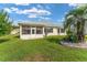Home backyard featuring a screened-in porch, green lawn, and tropical landscaping at 12489 Se 90Th Ter, Summerfield, FL 34491
