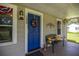 Charming front porch featuring a vibrant blue door, decorative wreath, and a cozy seating area at 1330 Ne 55Th St, Ocala, FL 34479