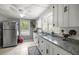 Sunlit kitchen features granite counters, stainless steel refrigerator, and modern white cabinets at 1330 Ne 55Th St, Ocala, FL 34479