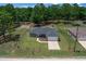 An aerial view of the property featuring a well-maintained lawn, fenced perimeter, and a paved driveway at 13479 Sw 100Th Ln, Dunnellon, FL 34432
