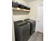 Well-equipped laundry room with gray washer and dryer and open shelf with storage baskets for organization at 13479 Sw 100Th Ln, Dunnellon, FL 34432