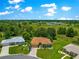 Aerial view of a single-story home with brown roof nestled among lush greenery with clear blue sky and scattered clouds at 13835 Se 85Th Cir, Summerfield, FL 34491