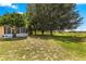 Large grassy backyard with mature trees and view of the screened patio at 13835 Se 85Th Cir, Summerfield, FL 34491