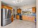 Open kitchen showcasing stainless steel refrigerator, wood cabinets, and tile floors at 13835 Se 85Th Cir, Summerfield, FL 34491