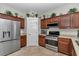 Modern kitchen boasting stainless steel appliances, wood cabinets, and tiled floors, perfect for culinary enthusiasts at 1443 Sw 161St St, Ocala, FL 34473
