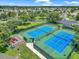 Aerial view of the community's two blue tennis courts, fenced playground, mature trees, and paved path at 1443 Sw 161St St, Ocala, FL 34473