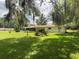View of the white home with a screen lanai and large backyard shaded by trees, with beautiful Spanish moss at 1523 Se 80Th St, Ocala, FL 34480