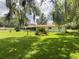 View of the white home with a screen lanai and large backyard shaded by trees, with beautiful Spanish moss at 1523 Se 80Th St, Ocala, FL 34480