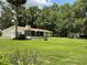 Ranch-style home with a spacious lawn, mature trees, and a detached garage on a sunny day at 1523 Se 80Th St, Ocala, FL 34480