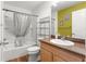 Bathroom featuring bathtub with shower, toilet, wood vanity sink and green accent wall with nautical artwork at 1751 Brandenburg Ct, The Villages, FL 32163