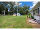Large backyard with mature trees, utility sheds, lush landscaping, and a wooden fence at 2340 Ne 14Th Ave, Ocala, FL 34470