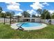 The fenced in backyard features a tranquil in ground pool surrounded by a grassy area and lounge seating at 2340 Ne 14Th Ave, Ocala, FL 34470