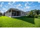 Home's backyard featuring a lush lawn, screened-in porch and partial view of the house at 3948 Se 4Th Ter, Ocala, FL 34480