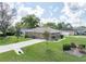 A home with an attached garage, well-maintained lawn, and mature trees providing shade at 5347 Pecan Rd, Ocala, FL 34472
