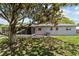 A spacious backyard featuring a screened porch, concrete patio, and ample greenery under a mature tree at 5500 Se 2Nd Pl, Ocala, FL 34480