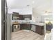 Kitchen featuring dark wood cabinets, granite countertops, stainless steel appliances, and a view to the living room at 6 Sequoia Loop, Ocklawaha, FL 32179