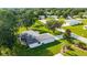 An aerial view showcases a white house with a screened patio and landscaped yard, surrounded by mature trees and greenery at 6113 Sw 101St Pl, Ocala, FL 34476