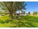 The home's backyard features a lush green lawn and the back of the home with a screened patio at 6113 Sw 101St Pl, Ocala, FL 34476