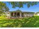 Exterior view of the rear of the house showcasing a screened patio and landscaped yard at 6113 Sw 101St Pl, Ocala, FL 34476