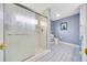 This bathroom features blue tile, a glass-enclosed shower, a toilet, and light fixtures at 6330 Sw 117Th Loop, Ocala, FL 34476