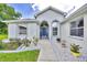 Close-up of the home's entrance features an elegant blue door, arched windows and stone landscaping at 6330 Sw 117Th Loop, Ocala, FL 34476