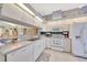 Well-lit kitchen with white cabinetry, white appliances, tile floors, and a breakfast bar that looks into another room at 6330 Sw 117Th Loop, Ocala, FL 34476