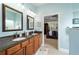 This bathroom has a double vanity with granite countertops, framed mirrors, modern lighting, and adjoins the primary bedroom at 7454 Sw 101St Ave, Ocala, FL 34481
