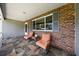 Relaxing front porch boasts tiled floors, comfortable chairs, and a brick accent wall for a cozy and welcoming entrance at 8461 Sw 109Th St, Ocala, FL 34481