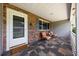 Inviting front porch features a tiled floor, comfortable seating, and a brick accent wall for a cozy outdoor space at 8461 Sw 109Th St, Ocala, FL 34481