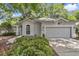 Single-story home featuring a gray exterior, manicured bushes, and an attached two-car garage at 8775 Sw 192 Ct, Dunnellon, FL 34432