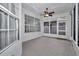 The screened porch features a ceiling fan, large windows, and neutral carpeting at 8775 Sw 192 Ct, Dunnellon, FL 34432