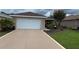 Spacious driveway leading to a two-car garage, complemented by lush greenery at 9047 Sw 102Nd Cir, Ocala, FL 34481