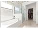 Bright bathroom featuring a soaking tub, glass shower, and access to the walk-in closet at 9120 Se 125Th Loop, Summerfield, FL 34491