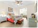 Bright bedroom with a queen bed, colorful bedding, a ceiling fan and wood-look floors at 9120 Se 125Th Loop, Summerfield, FL 34491