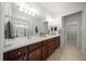 Bathroom featuring double sinks, vanity with brown cabinets, and enclosed glass shower at 9948 Sw 69Th Ln, Ocala, FL 34481